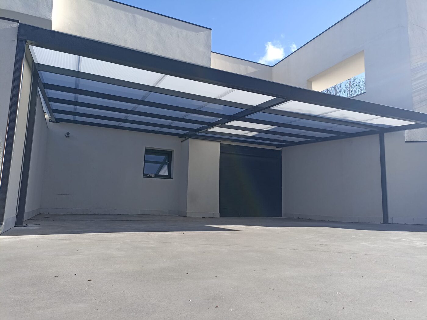 Carport adosado a vivienda con paredes blancas