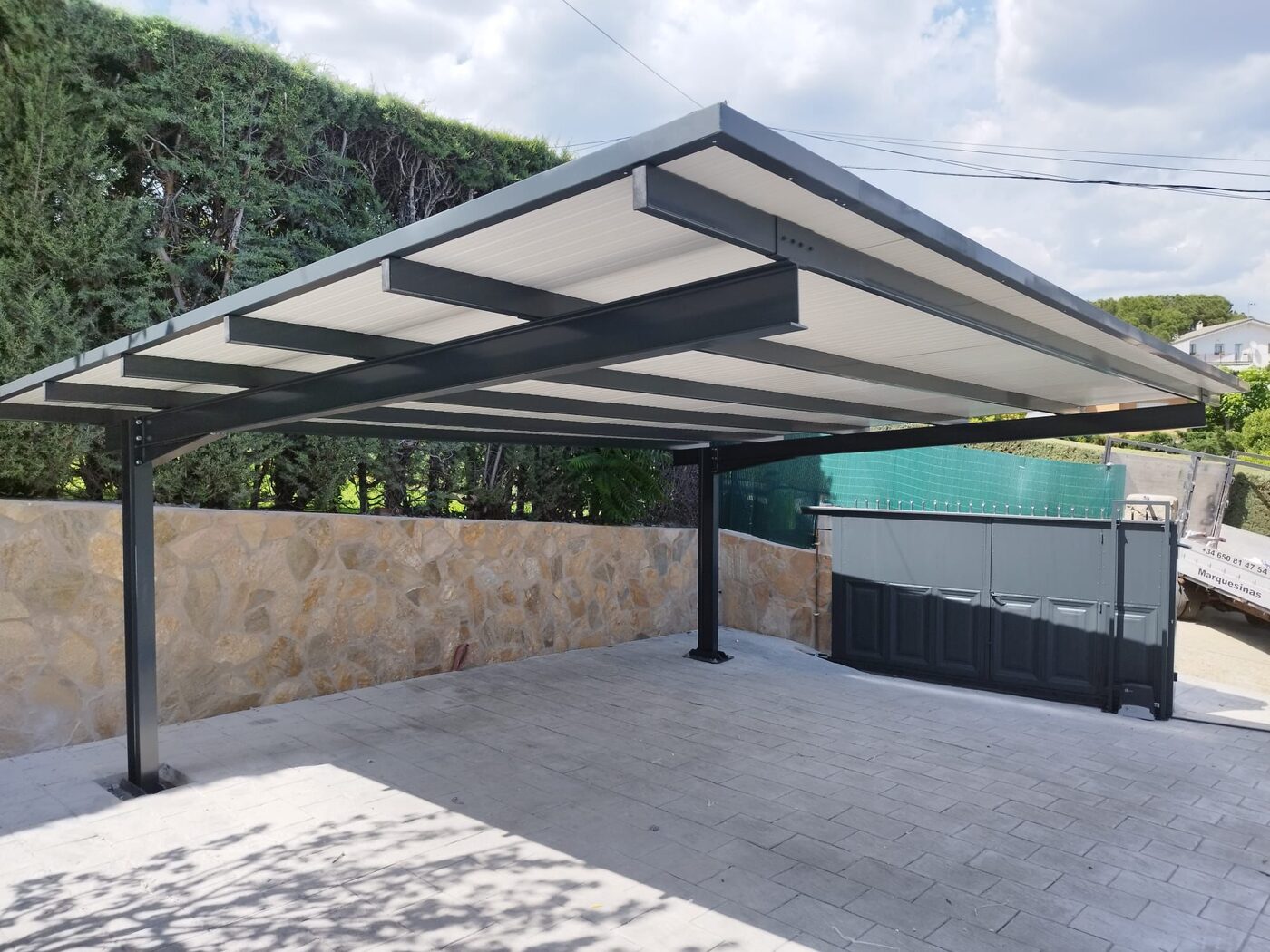 Carport con cubierta plana junto a seto verde